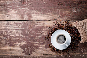 Coffee cup and beans on a wooden table.