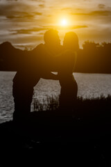silhouette of romantic lovers with river in thailand with sunset