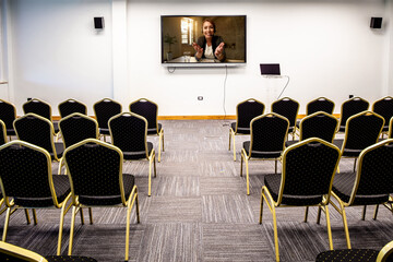 Happy businesswoman holding video conference in empty convention center.