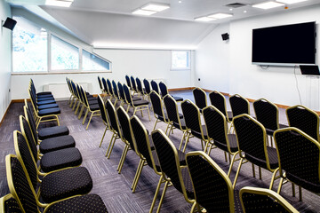 Conference hall empty seats and projection screen before a seminar.