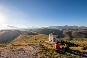 People looking sunset, relax in medieval ruins of Rocca Calascio church with beautiful landscape in background. Relax in mountain with hills and forest at dusk, hiking and trekking tourism travel