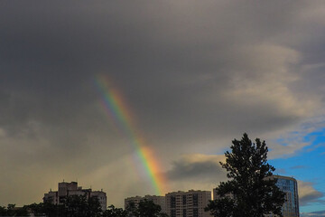 Rainbow over the city after the rain against the dark clouds