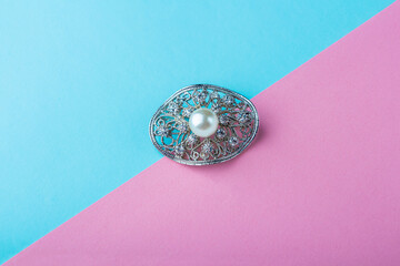 Vintage pearl jewelry brooch on pink blue background. Elegant gift for woman. - obrazy, fototapety, plakaty