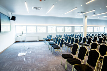Empty congress center with seats and projection screen on the wall.