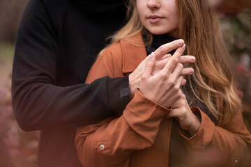 beautiful hands close-up, in love with a couple, a guy hugs a blonde girl, a marriage proposal, a woman in a coat, dark tones