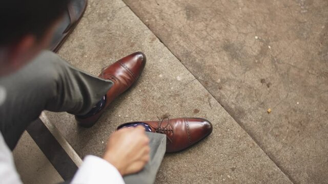 Groom ties brown leather shoes before his big wedding. Top down view/ over the shoulder. 
