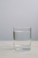 Light minimalistic photo of glass with clean water on grey background