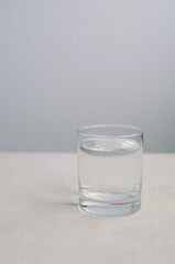 Light minimalistic photo of glass with clean water on white background