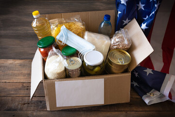 Cardboard box with oil, canned food, cereals and pasta.