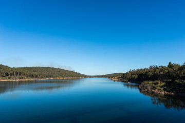 Fototapeta na wymiar Mundaring Weir dam and its tranquil water in the afternoon on a late Winter day.