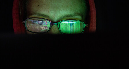 hacker at computer data reflecting in eyeglasses