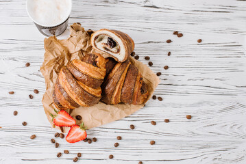 Fresh croissants with chocolate and strawberries on the wooden background