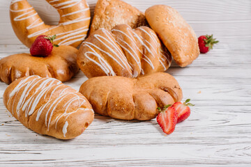Different fresh buns on the white wooden background