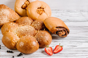 Different fresh buns on the white wooden background