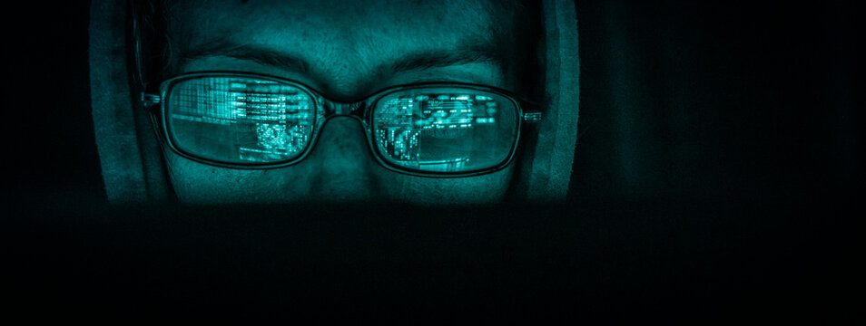hacker at computer data reflecting in eyeglasses