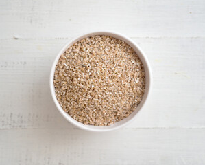 Wheat groats in a bowl on wooden background