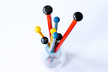 Colourful knitting needles (red, green, yellow, blue) in detail in a glass vase as seen from on top