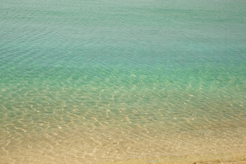 Sea background. Blue sea, sand and small pebbles. different color stripes of water and sand.