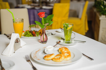 Breakfast in empty restaurant. Сheese pancakes or syrniki on the table. Differential focus