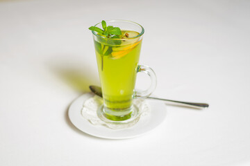 Close-up of green mint tea with lemon on white. Breakfast in empty restaurant.