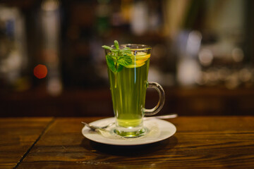 Green mint tea with lemon on bar counter. Breakfast in empty restaurant.
