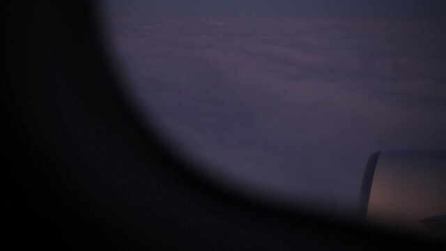 View from flying plane at dark night sky with white fluffy clouds.