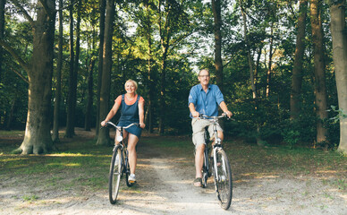 Naklejka premium Active seniors riding bike in summer nature. Old people healthy lifestyle and sport concept