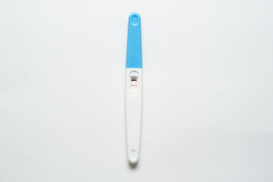 Pregnancy test pack hold by hand on top of white background.
