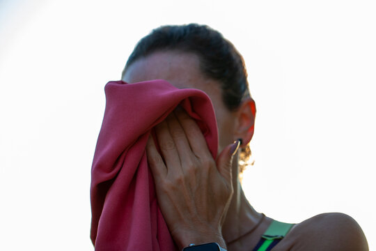 Mujer sec&aacute;ndose el sudor con toalla. Deporte.
