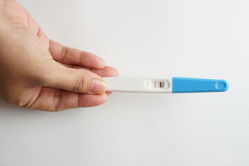 Pregnancy test pack hold by hand on top of white background.