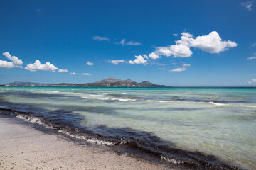 Mallorca sea beach view after storm. Sea water of different colours. White clouds, blue sky, sunny summer day. Holidays in Spain.