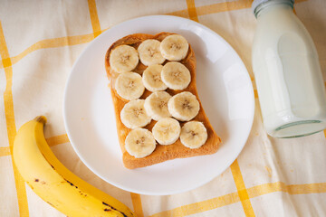 Home made organic sliced bread with banana on top and bottle of milk.