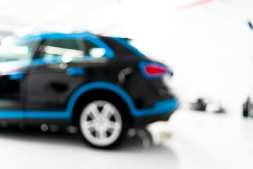 Blurred abstract image of man worker with car in a body shop. Blur car auto service. Car bokeh. Blurred background with car in garage. Vehicle maintenance in auto repair service. 