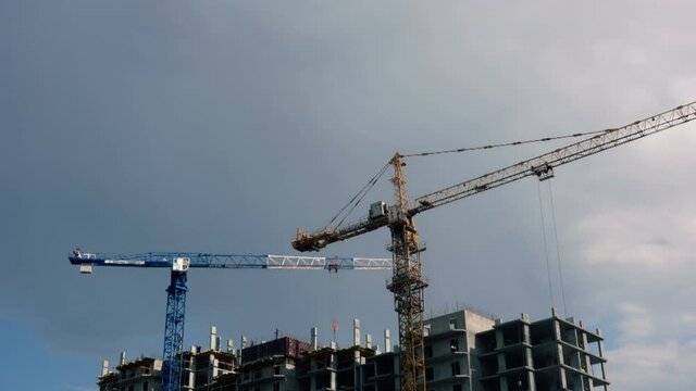 Construction site with cranes against a cloudy sky. Time Laps. Construstion Concept
