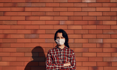 Naklejka premium Confident woman in mask against brick wall