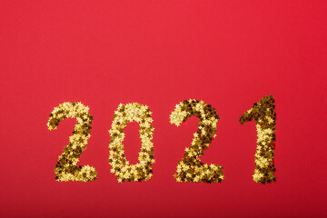 Gold stars sparkle in the shape of the number 2021 on a red background.