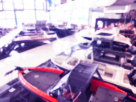 Blurred Background With Fishing Motor Boat In The Dealership Store. Blur Motorboat Showroom Background. Bokeh Light