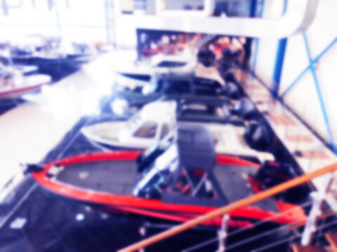 Blurred Background With Fishing Motor Boat In The Dealership Store. Blur Motorboat Showroom Background. Bokeh Light