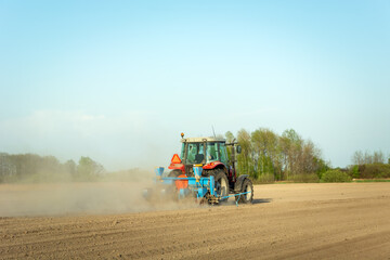 Tractor ploughing the field, dust from dry soil