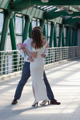 A young bride and groom kiss on an elevated crossing. Wedding. Wedding walk.