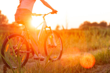 Close up. Joyful young woman riding a bicycle at the riverside and meadow promenade. Inspired by...