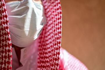 Arabic man from Saudi Arabia wearing traditional clothes using face mask to protect himself from...