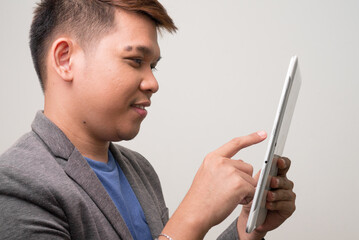 Profile view of happy young Asian businessman using digital tablet