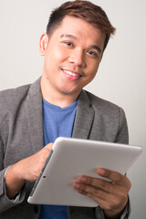 Portrait of happy young handsome Asian businessman using digital tablet