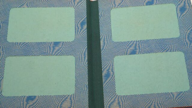Closeup point of view video of woman turning pages of old vintage cardboard paper photo album with empty green spaces for pictures.