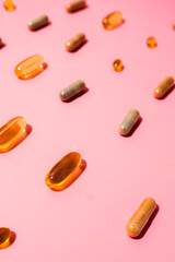 Top view of pills on pink pink background with harsh shadows. Trendy flatlay of preventive medicine