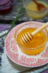 Two glass bowls with fresh natural lavender honey, jars with honey and lavender flowers on wooden background.
