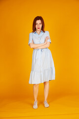 Smiling redhead girl on yellow background blue dress