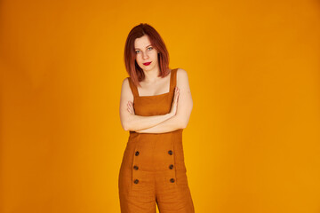 Smiling redhead girl on orange background orange overalls