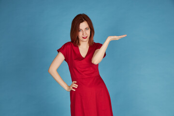 Smiling redhead girl on blue background red dress